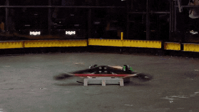 slow motion gif of a combat robot hitting another robot and flinging it through the air while being filmed by an aerial drone